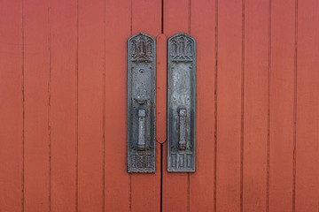 Rustic door handles on a red painted door of an old church