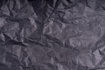 Dark wrinkled creased black paper poster texture. Blank crumpled grainy paper textured surface. Smudged grungy cardboard with fiber. Close up. Material tissue for packing