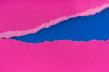 Pieces of torn ragged purple paper edges on blue background. Ripped cracked paper edge isolated with soft shadow. Paper piece torn edge. Copy space, frame, banner