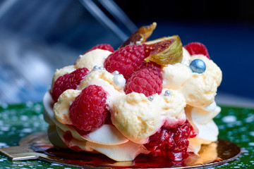 Close up of dessert Pavlova with raspberries and figs on green plate