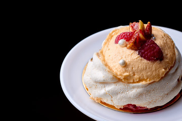 Close up of dessert Pavlova with raspberries and figs against a dark background