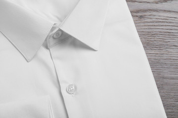 Stylish white shirt on wooden table, closeup. Dry-cleaning service