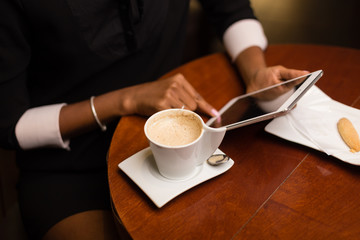 Black african american young yoman drinking coffee and using a tablet