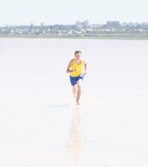 Fototapeta na wymiar Man running in water on the beach