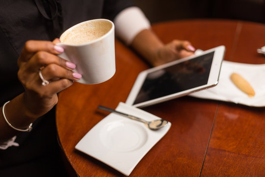 Black african american young yoman drinking coffee and using a tablet