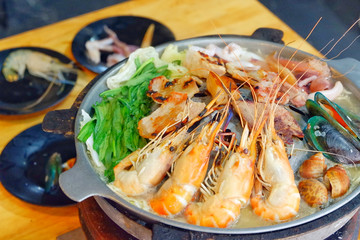 Sliced Pork and seafood on Thai Styled Coal Grill and Shabu Pan.Shrimp Clams in a Hot Pan.Close up.
