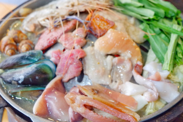 Sliced Pork and seafood on Thai Styled Coal Grill and Shabu Pan.Shrimp Clams in a Hot Pan.Close up.
