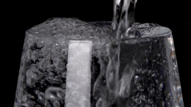 Overflow water wastage in a transparent glass closeup 