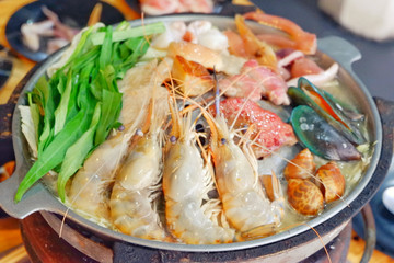 Sliced Pork and seafood on Thai Styled Coal Grill and Shabu Pan.Shrimp Clams in a Hot Pan.Close up.
