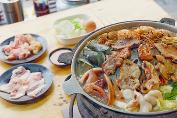 Sliced Pork and seafood on Thai Styled Coal Grill and Shabu Pan.Shrimp Clams in a Hot Pan.Close up.

