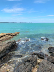 Rocks extending into the sea.View of the sea and a wooden bridge extending into the sea, with Thai characters written as 