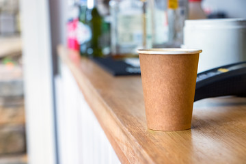 A disposable coffee cup made of recycled paper on a coffee shop counter.