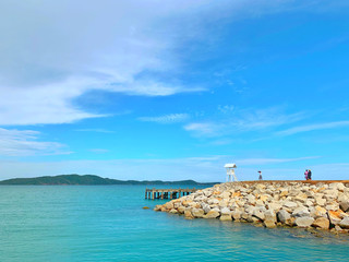 Rocks extending into the sea.View of the sea and a wooden bridge extending into the sea, with Thai characters written as " Khao Laem Ya " on a pier made of stone.Close up.