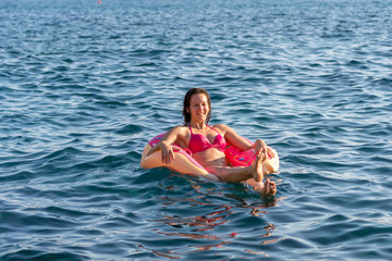 Handsome young woman in pink bikini smiling and enjoying the waves