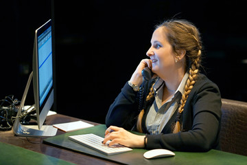 Fototapeta na wymiar Portrait of office worker, manager woman secretary answering phone calls and talking with customers. Night time. The concept of service.
