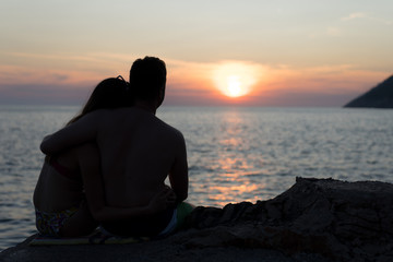 Silhouette of a young couple at the beaching watching the sunset