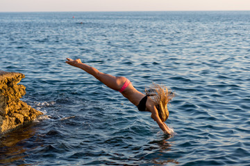 Handsome young woman diving into the sea