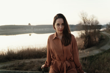 Portrait of young woman by lake at sunset