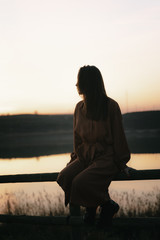 Portrait of young woman by lake at sunset