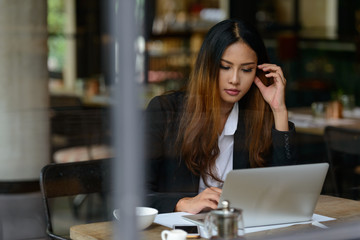 Young beautiful Asian businesswoman using laptop at the coffee shop