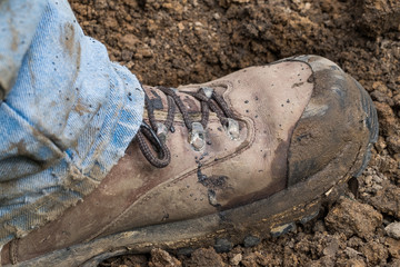 Muddy work boot stepping on dirt