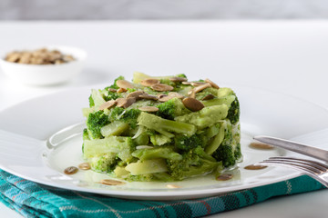 Boiled broccoli with pumpkin seeds on a white plate on the table