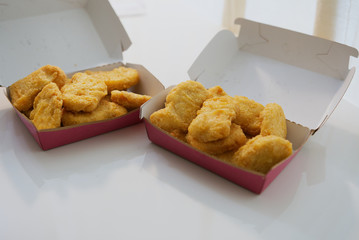Close shot of chicken nuggets in a tray on a minimal white table