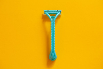 Blue razor on a yellow background top view. The concept of hygiene, beauty, shaving.