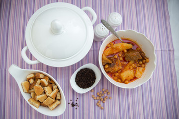 Kufta bozbash . A bowl of white ceramic salt and pepper. Dried bread crumbs in a bowl, black pepper . Bowl of Bozbash - delicious Azerbaijan national soup on the table with white flowers .