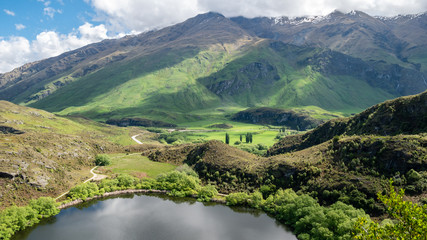 Fototapeta na wymiar Small lake with lush green hills, landscape shot made in New Zealand