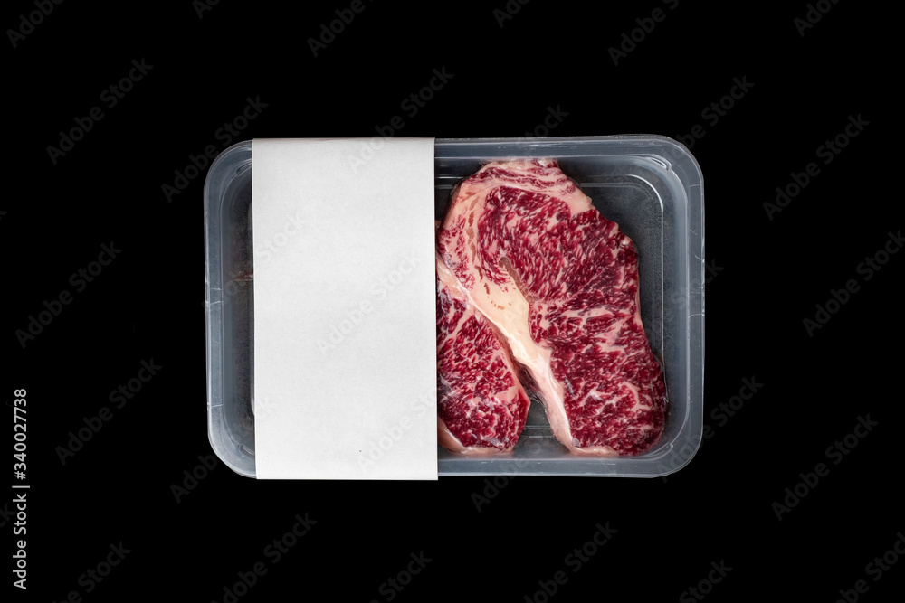 Wall mural raw striploin marbled beef steak vacuum packed isolated on black, logo mockup