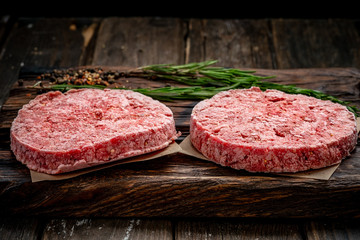 Organic frozen raw minced meat or beef cutlets on a wooden Board 