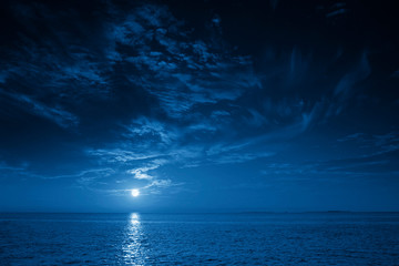 This photo illustration of a deep blue moonlit ocean and sky at night  would make a great travel background for any travel or vacation purpose. - obrazy, fototapety, plakaty