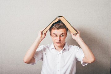 man with glasses holding an open book on his head