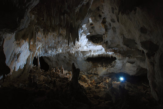 The Light Of The Headlamp In A Beautiful Cave Hall With Stalactites And Stalagmites