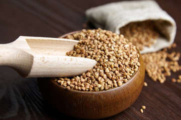 Buckwheat groats (hulled seeds) in wooden bowl with scoop