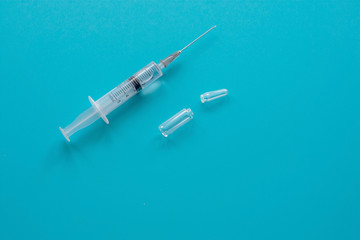 Syringe for injection and ampoule on a blue background. The concept of medicine, healthcare. Flat lay, copy space.