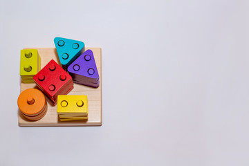 Children's toy made of wood on a white background close-up, the child plays with a constructor, a sorter. Children's room with toys. Constructor in the hands of a child. Wooden houses on the backgroun