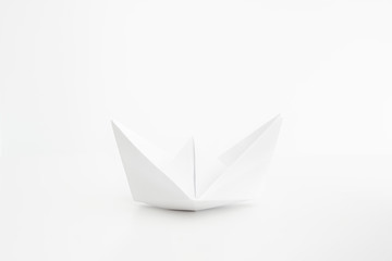 White folded paper boat frontal shot isolated on bright background