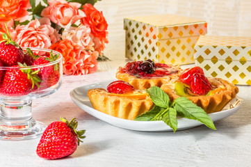 Festive still life with cakes, strawberries, gift boxes