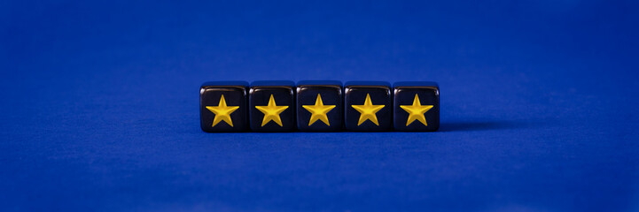 Five gold stars ranking on black cubes in conceptual image of online feedback or customer review...