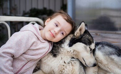 A girl hugs her dog. A dog is a person's best friend. Husky dog. Friendship of a girl and a dog. Husky black with gray.