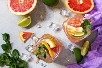 Summer ice refreshing drink. Fresh mojito cocktail with grapefruit, lime and mint in a glass on a gray stone background. Top view flat lay background.