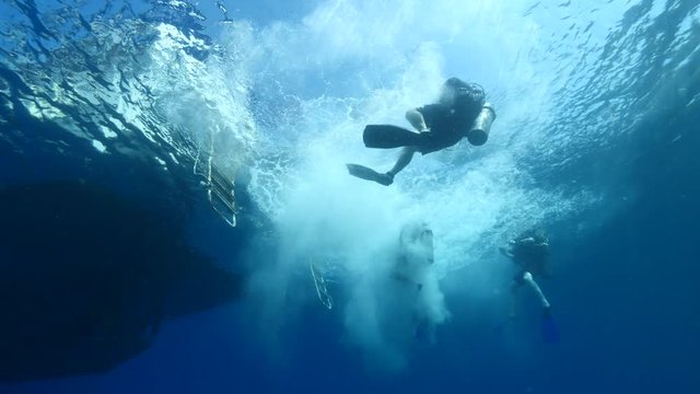 scuba divers jumping in water from boat underwater ocean scenery