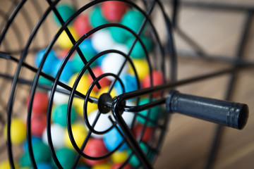 A close up of a bingo cage filled with multi-colored balls. Each ball has a letter and number on it...