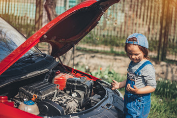Obraz premium Little child trying to fix broken real car. Dreaming to be auto technician