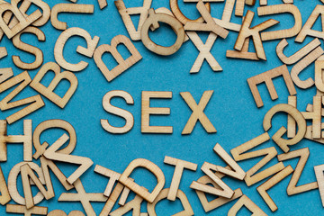 Wort SEX aus Holzbuchstaben auf blauem Hintergrund

