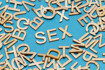 Wort SEX aus Holzbuchstaben auf blauem Hintergrund
