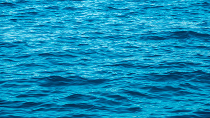 Ripples in the empty blue sea cause sparkles when light shine to surface at sunny day. Close up.