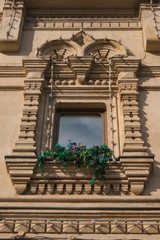 Beautiful vintage window on an old building with fresh flowers on a windowsill.